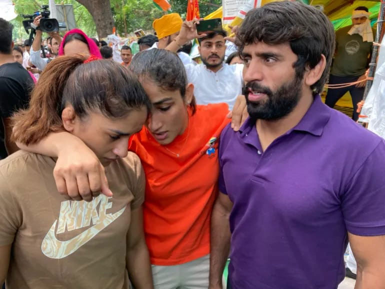 Indian wrestlers, from right, Bajrang Punia, Sangita Phogat and Vinesh Phogat talk ahead of their protest march towards the newly inaugurated parliament building in New Delhi